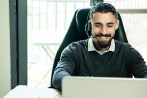 man working at a laptop wearing a headset