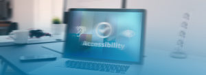 A laptop on a desk displays the word "Accessibility" with icons for hearing and visual aids, alongside a checkmark symbol. The background is blurred, highlighting the focus on accessibility.