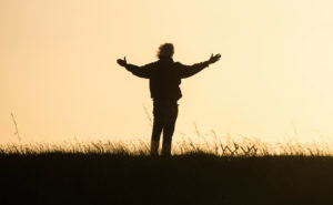 person standing in open outdoor space with hands spread