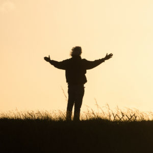person standing in open outdoor space with hands spread