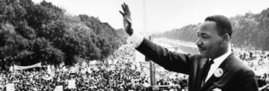 Martin Luther King Jr. waves to a large crowd during the 1963 March on Washington, with the Washington Monument visible in the background.
