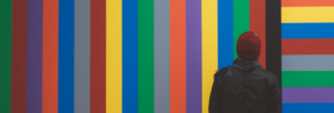Person standing in front of a multi-colored striped wall
