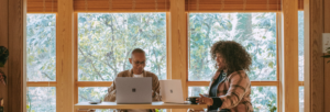 Two adults sitting at a table working on their laptops