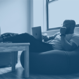 A man working on his laptop while laying down on a beanbag chair