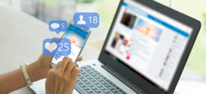 A person uses a smartphone beside a laptop, with social media icons displaying 25 likes, 5 comments, and 18 friend requests floating above the phone screen.