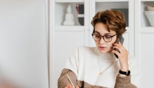 Modern businesswoman in casual outfit talking on mobile in office