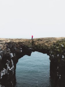 person crossing a natural arch over water