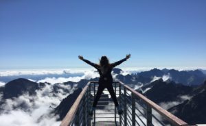 woman at the top of a mountain peak celebrating