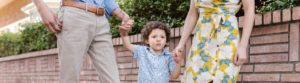 a child walking between two adults holding their hands