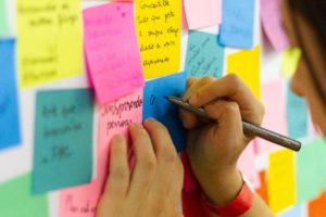 woman writing on wall sticky notes