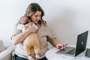 woman holding a baby using a laptop