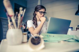 Photo of a Woman Thinking while looking at a laptop