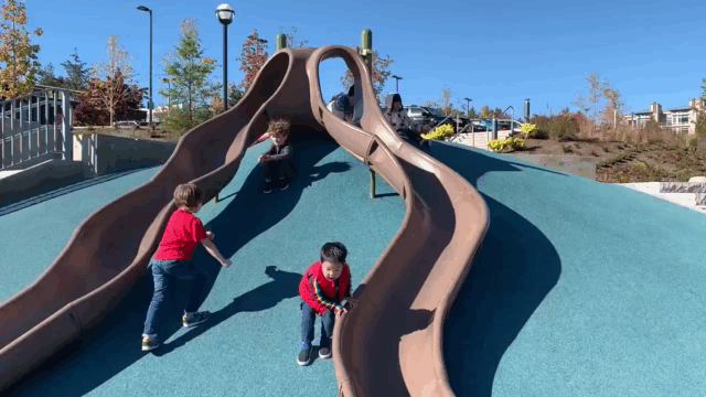 Children on a playground sliding down the ground next to slides
