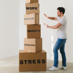 A man standing in front of huge boxes labeled stress, problems, anxiety, deadline, and work.