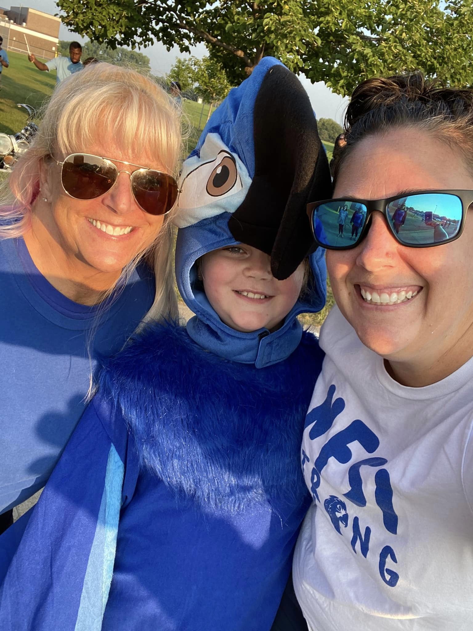 Student in parrot mascot outfit and two teachers smiling