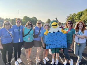 teachers and mascot outside in shirts with new logo