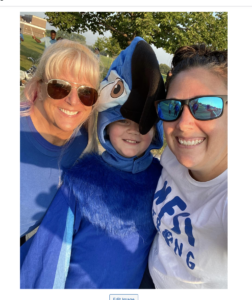 Student in parrot mascot outfit and two teachers smiling