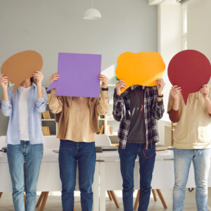 Teen students holding blank paper speech balloons.