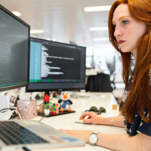 Woman working on website backend on her monitors