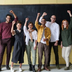 A group of people representing and alumni network cheering in an empty classroom