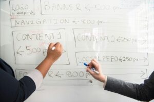 Person Holding Marker writing on whiteboard