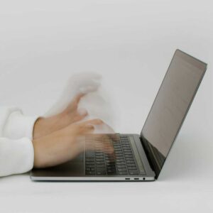 Hands typing an email quickly into their laptop, implying an emotional response