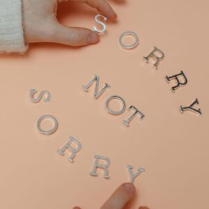 Hands moving silver letters to spell out "Sorry Not Sorry"