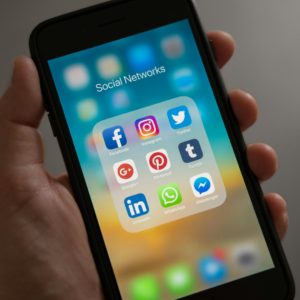 Hand holding a cell phone which is full of social media apps