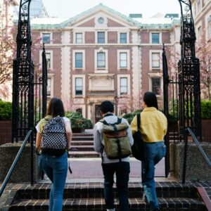 Students walking up steps toward a non-descript school building