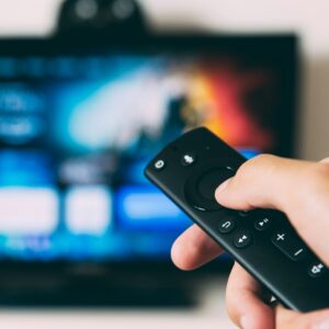 Hand using a television remote to turn up the volume on a Super Bowl Ad
