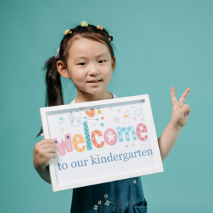 Child holding a 'welcome to our kindergarten' sign
